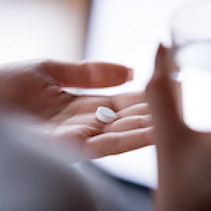 Close up woman holding pill in hand with water