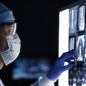 Male doctor in surgical clothes looking at vertebral mri scan