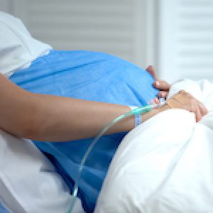 Pregnant woman holding blanket, feeling abdominal pain, risk of miscarriage