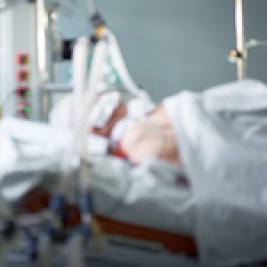 Coronavirus pandemic. Blurred image of intensive care emergency room with hemodialysis machine, ventilator. Patient with coronavirus in critical stance.