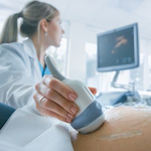 In the Hospital, Close-up Shot of the Doctor does Ultrasound / Sonogram Procedure to a Pregnant Woman. Obstetrician Moving Transducer on the Belly of the Future Mother.