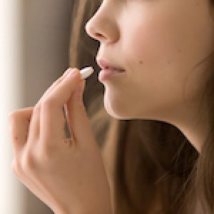 Close up image of woman drinking round white pill