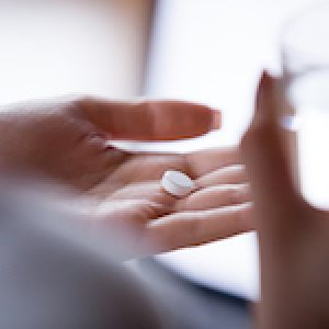 Close up woman holding pill in hand with water